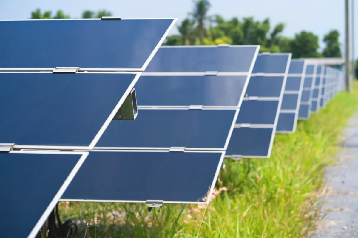 Rząd paneli fotowoltaicznych na polu, prezentując skalowalną instalację do zaspokojenia potrzeb energetycznych sklepu i warsztatu.