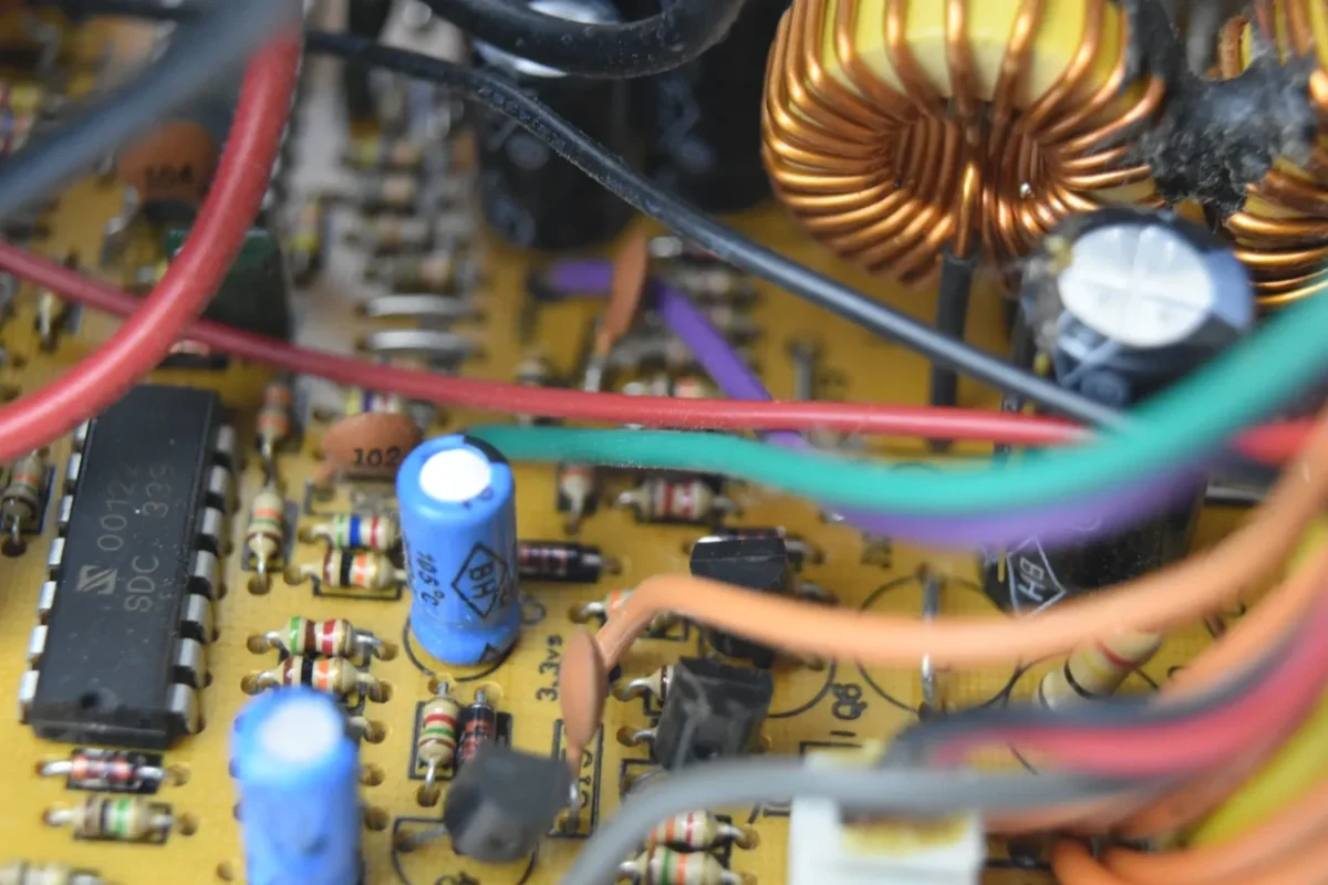 Elektroniczny układ z cewką i kondensatorami, przedstawiający wewnętrzną strukturę generującą dźwięk w inwerterze fotowoltaicznym.