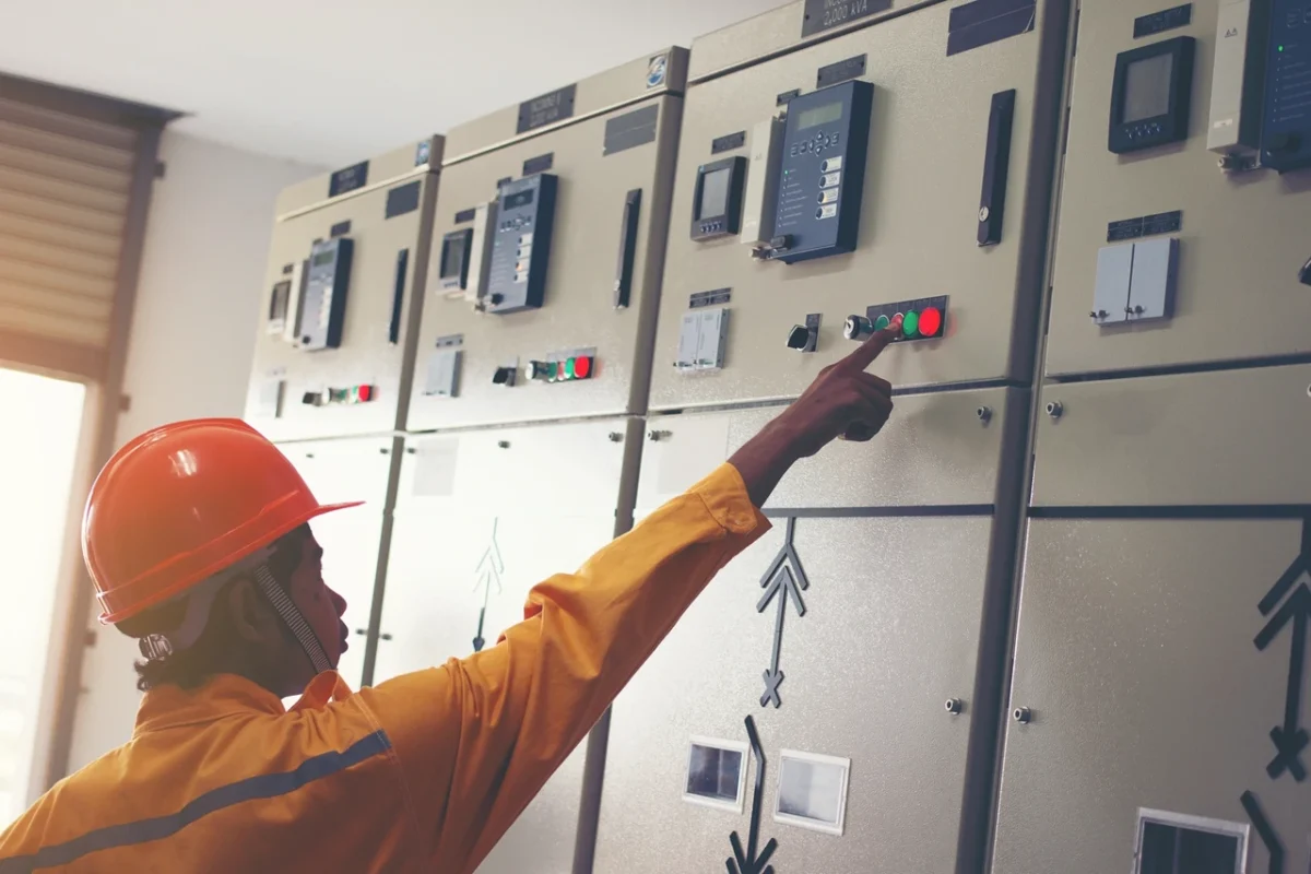 Inżynier elektryk obsługujący szafę rozdzielczą niskiego napięcia w celu pomiaru prądów fazowych i diagnostyki asymetrii obciążenia w trójfazowym hybrydowym systemie fotowoltaicznym.