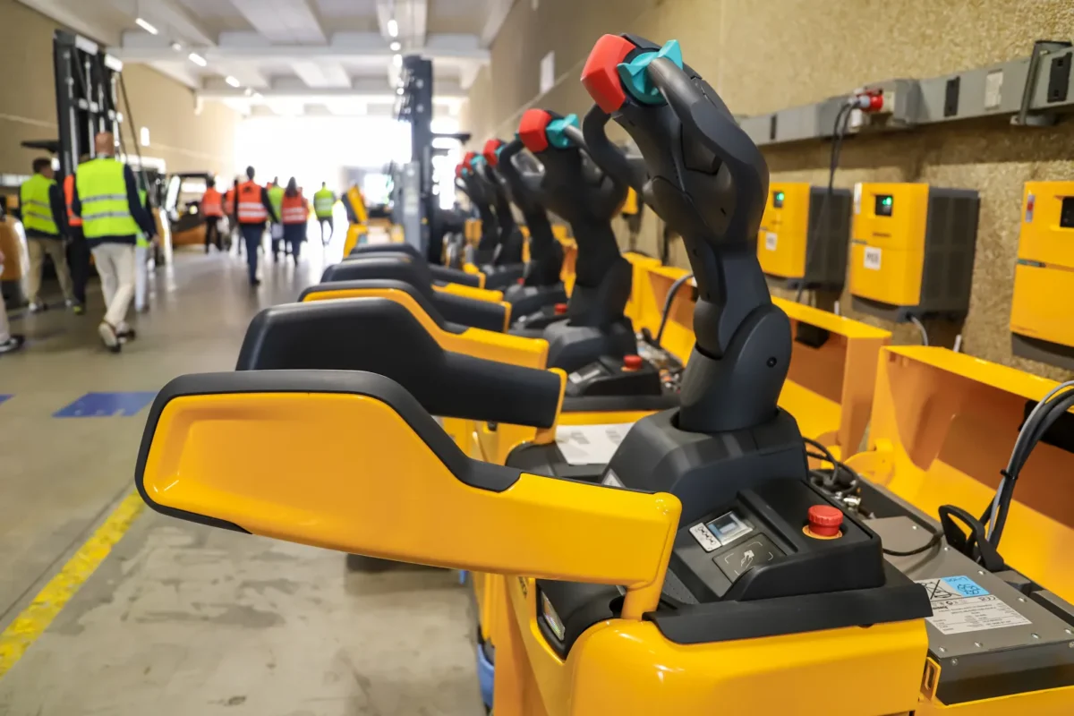 Wózki widłowe elektryczne w magazynie logistycznym przygotowane do ładowania energią słoneczną