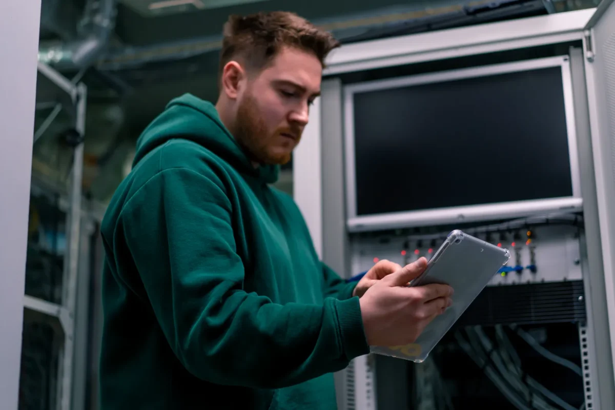 Technik sprawdza stan urządzeń na tablecie w serwerowni.