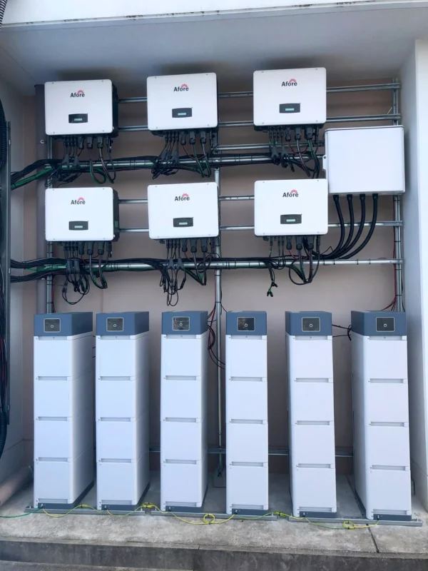 Zestaw zamontowanych falowników i akumulatorów magazynujących energię słoneczną, sprzęt służy do wyrównywania oraz redukcji skoków napięcia w sieci fotowoltaicznej.
